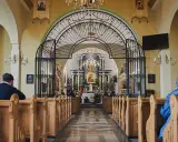 Wnętrze sanktuarium Matki Bożej Pięknej Miłości w Polańczyku. Wierni siedzą w ławkach, patrząc na ołtarz.