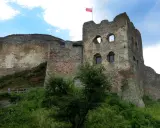 Ruiny zamku Czorsztyn na wzgórzu, z polską flagą powiewającą na wieży.