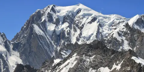 Majestatyczny, ośnieżony szczyt, gdzie jest Mont Blanc, góruje nad skalistym, pokrytym śniegiem zboczem.