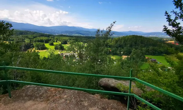 Widok z góry Witosza na zielone doliny, lasy i odległe pasmo górskie.