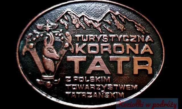 Okrągły medalion z napisem "Turystyczna Korona Tatr" i wizerunkiem kozicy. Symbolizuje zdobywanie szczytów i piękno Tatr.