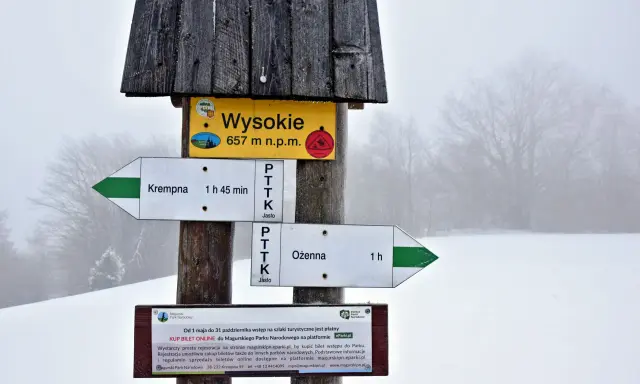Szlak w Magurskim Parku Narodowym. Znak wskazuje Wysokie (657 m n.p.m.), najwyższy szczyt, oraz kierunki do Krempnej i Ożennej.