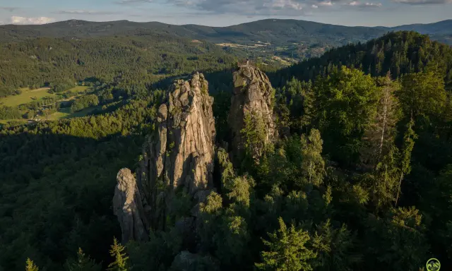 Skaliste szczyty, jak sokolik duży, górują nad lasem. Na jednym z nich platforma widokowa z turystą.