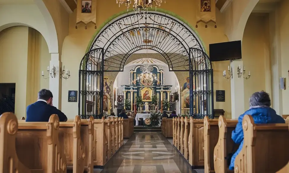 Wnętrze sanktuarium Matki Bożej Pięknej Miłości w Polańczyku. Wierni siedzą w ławkach, patrząc na ołtarz.